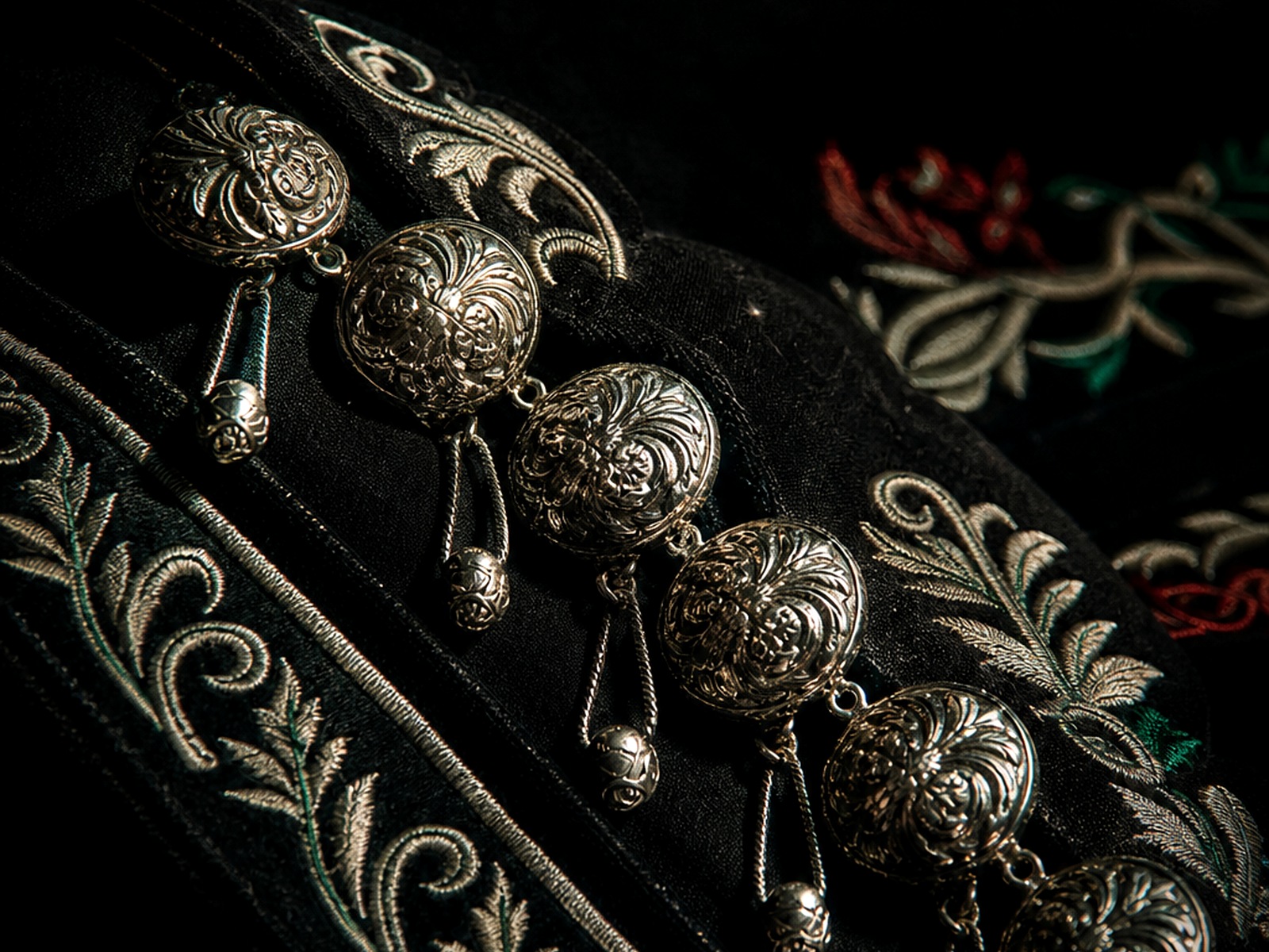 Detalle de botonadura y bordado plateado sobre traje de charro negro.